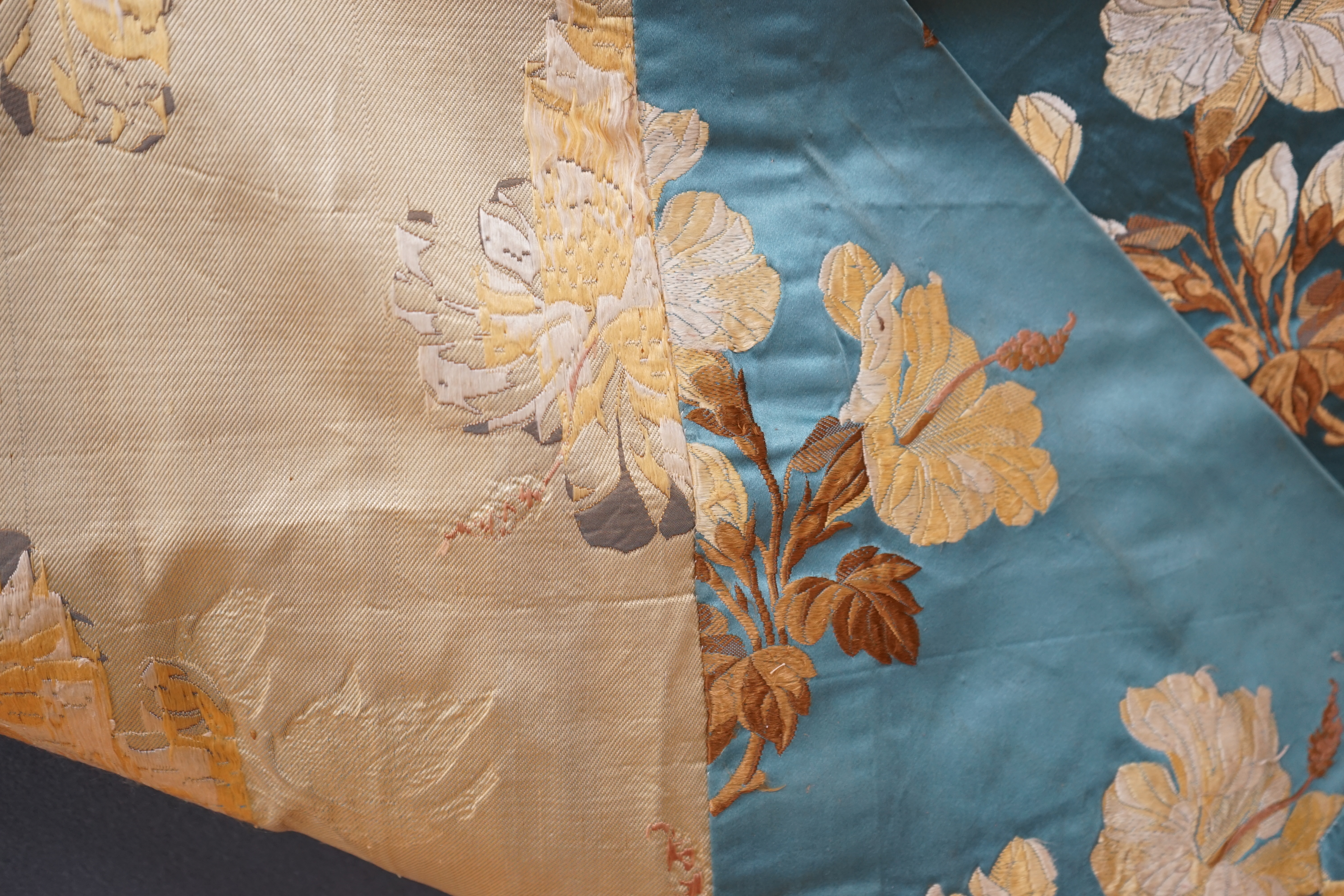 A turquoise satin floral silk brocaded panel of four 59cm widths, boldly embroidered in yellow and brown strays of lilies, the panel possibly part of a pelmet or half tester bed, each spray being 21cm high as a diagonal